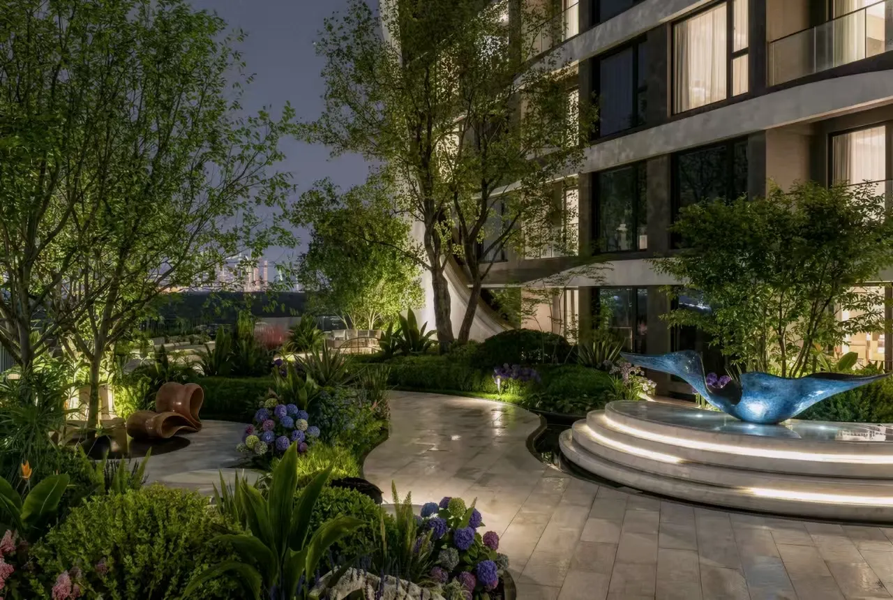 A landscaped evening garden beside the curved residential façade.